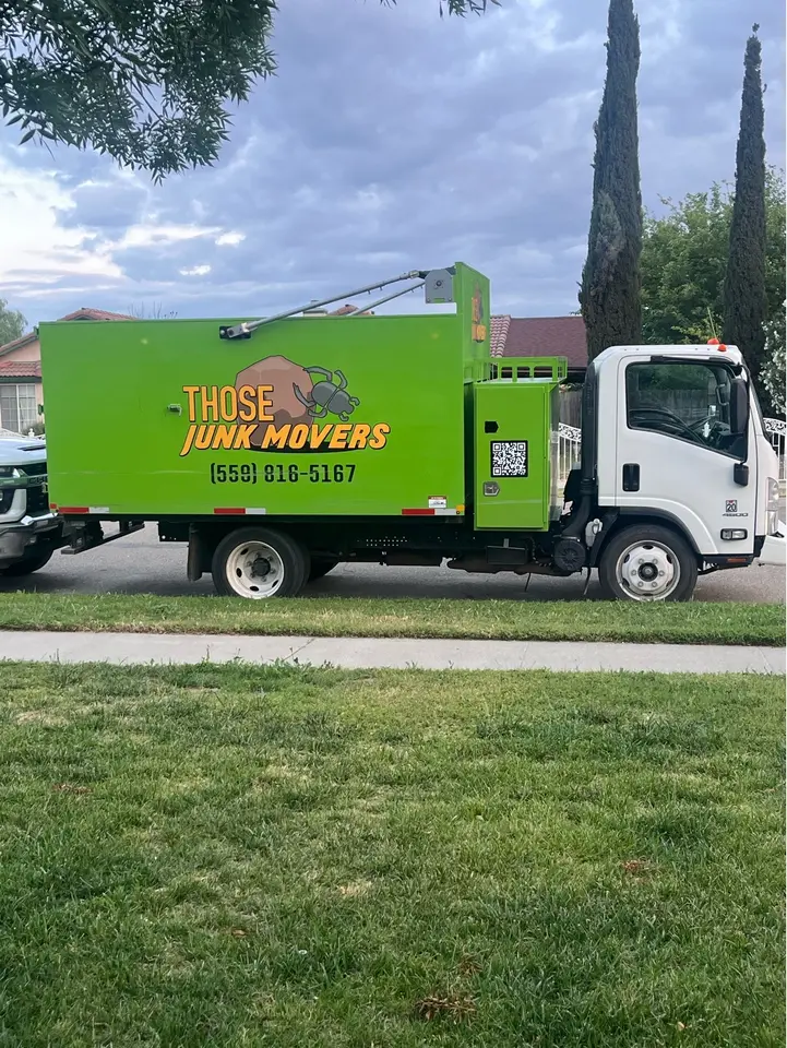 The green Those Junk Movers box truck parked on a residential street